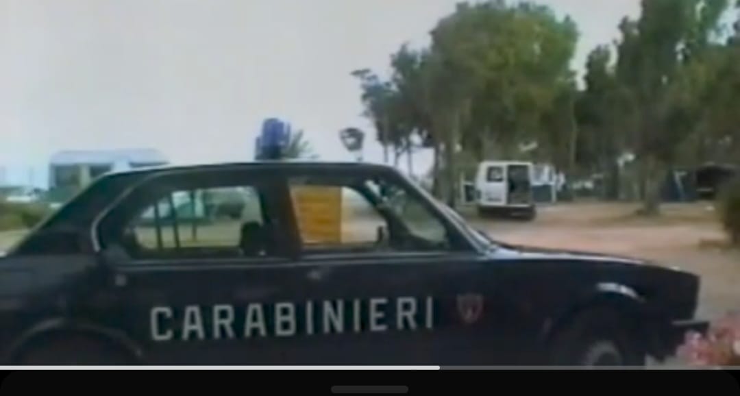 Grainy shot of a dark blue Italian police car with the word “Carabinieri” in capitals along its side.